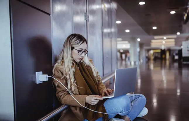 Mulher em aeroporto com o notebook ligado